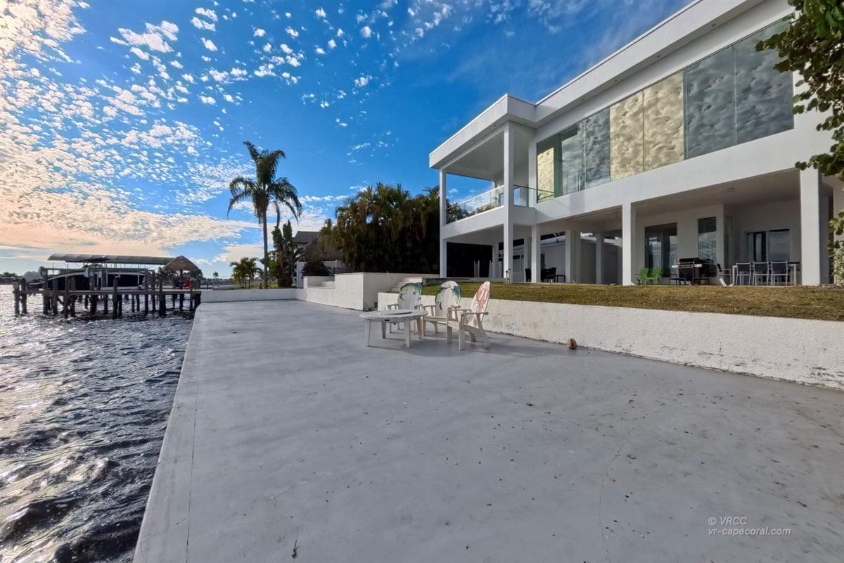 Modern waterfront house with patio and palm tree
