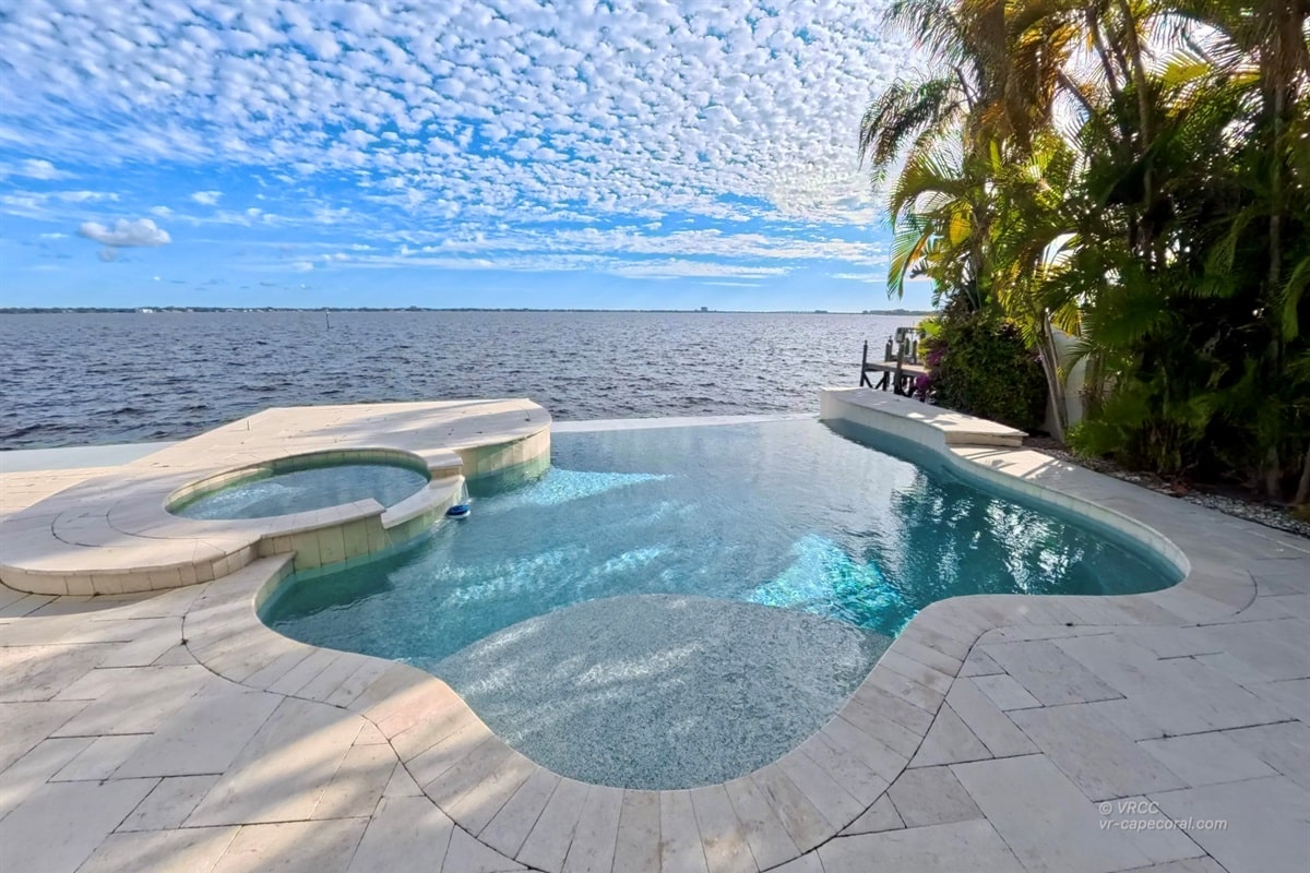 Infinity pool overlooking a lake with palm trees.
