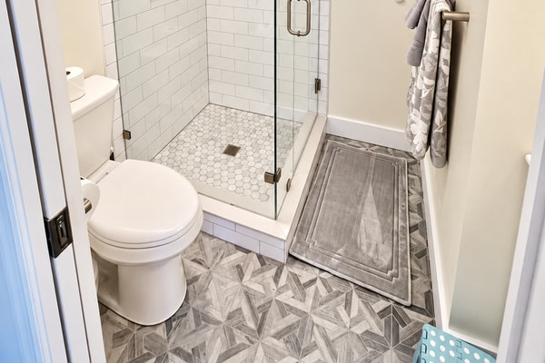 Modern bathroom with glass shower, toilet, and patterned tile