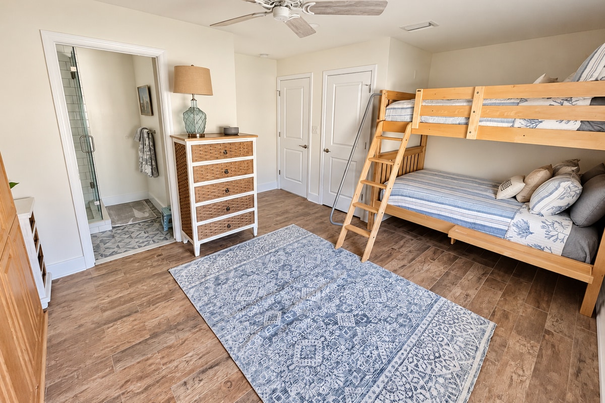 Coastal-style bedroom with wooden bunk bed and blue rug