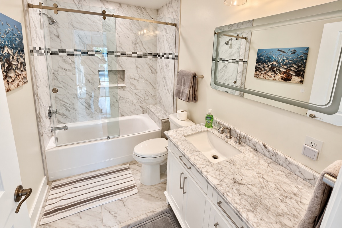 Bright marble bathroom with glass shower and white vanity